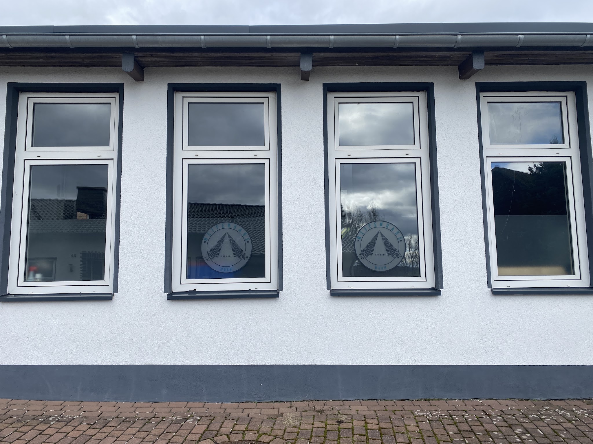 Die Halle der ReifenOase Much mit dem Firmenlogo in den Fenstern